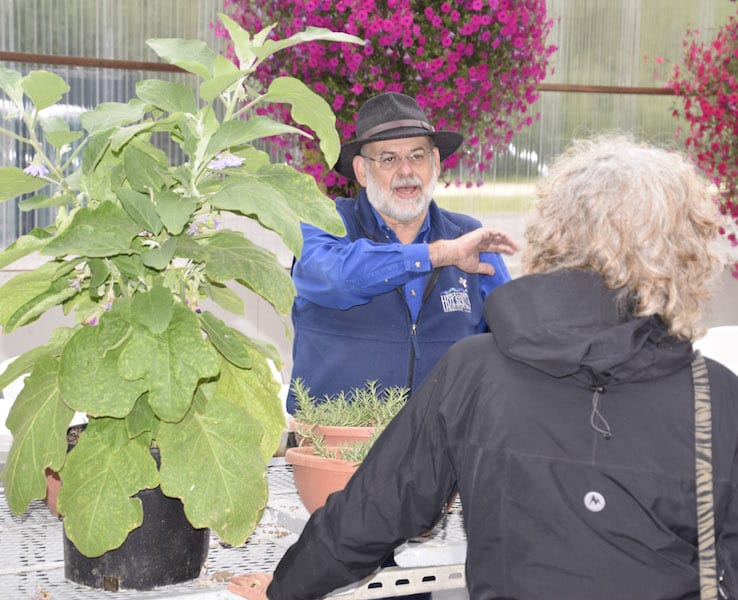 Chena Hot Springs Resort owner Bernie Karl leads a tour group through a flower and plant cultivation display at the resort.