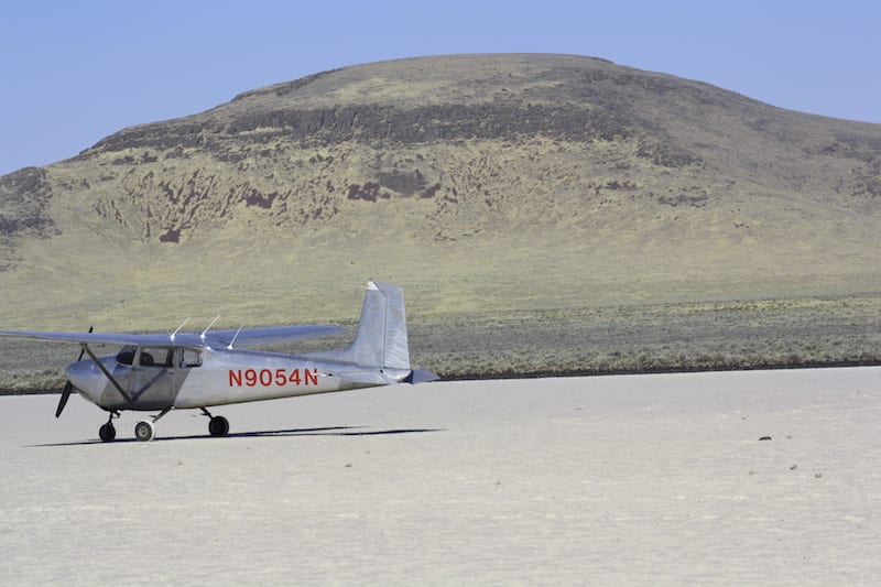 Bob's plane by a dry lake bed.