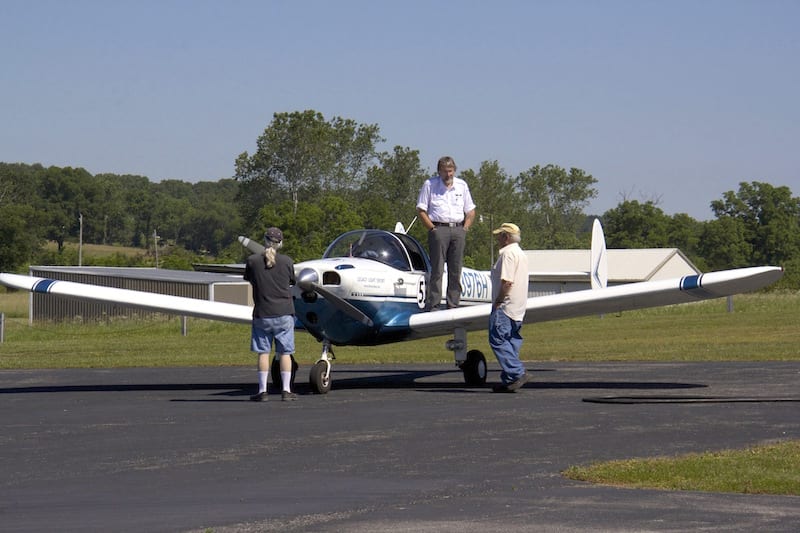 Enjoying the ride. Air racer William E. Dubois chats with local pilots at a fuel stop at Willow Springs, Missouri (1H5), in route to the 2016 Big Muddy Air Race. Race 53 has a limited range, requiring 200-mile legs on cross countries to reach the SARL races, but Dubois reports enjoying visiting so many small airports and meeting the locals. (Photo by Lisa F. Bentson)