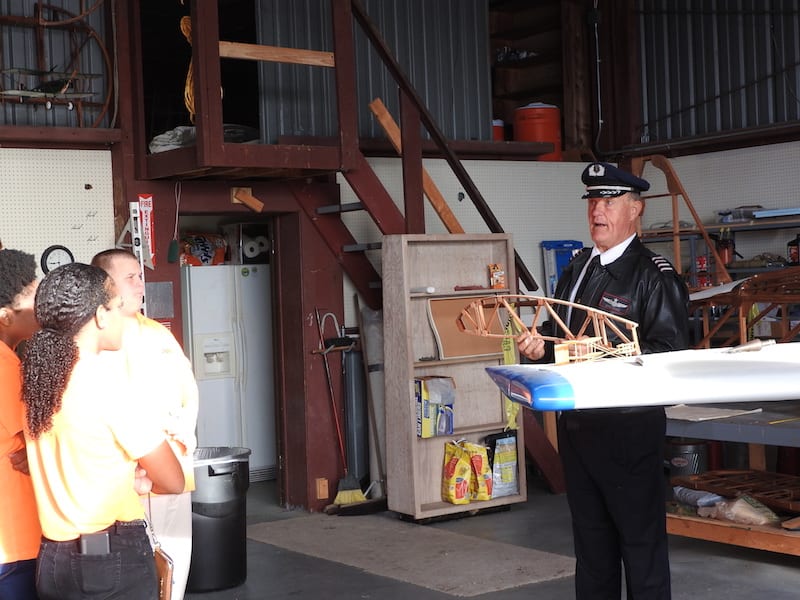 Retired American Airlines captain Steve Barber explains some of the finer points of the theory of flight to the Spark students in the EAA hangar.